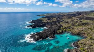 Aerial view of Galapagos Islands volcanic coastline where black lava flows meet turquoise Pacific waters