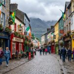 Colorful High Street in Killarney town with traditional Irish pubs and shops, mountains visible in the background