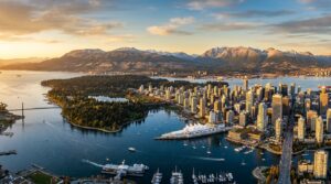Panoramic view of Vancouver showing downtown skyline, Stanley Park, and North Shore Mountains with harbor waters