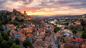 Tbilisi Old Town with traditional wooden balconies, Narikala Fortress, and sulfur bath domes at sunset