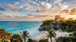 Wide-angle golden hour photograph of the ancient Tulum Mayan ruins perched on limestone cliffs